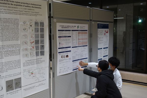 人々が室内でポスター展示を見ながら議論している様子。学生や研究者が情報を共有しています。