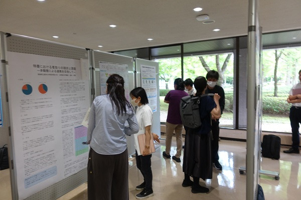 廊下で実施されるポスターセッションに参加する学生や医療関係者たち。研究内容の説明に熱心に耳を傾けている様子。