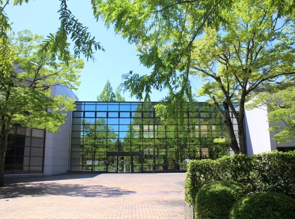 福島県立医科大学のキャンパス風景、緑豊かな木々とガラス張りの建物が映える。