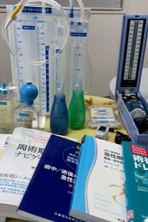 成人看護学に関連する医療器具や教科書が並ぶ作業台の様子。