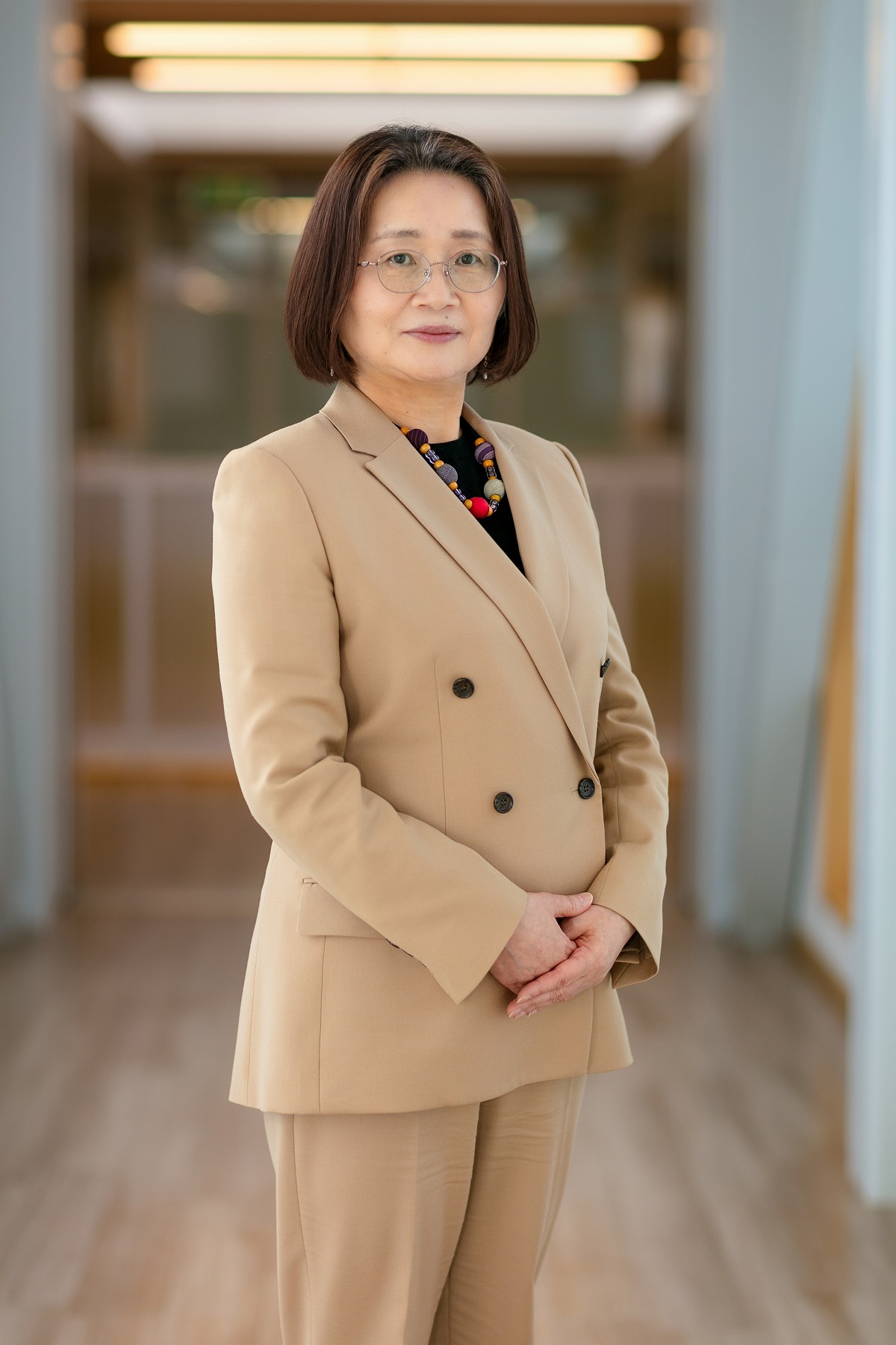 看護学研究科長の坂本祐子氏が、明るい室内でスーツ姿で立っている写真。