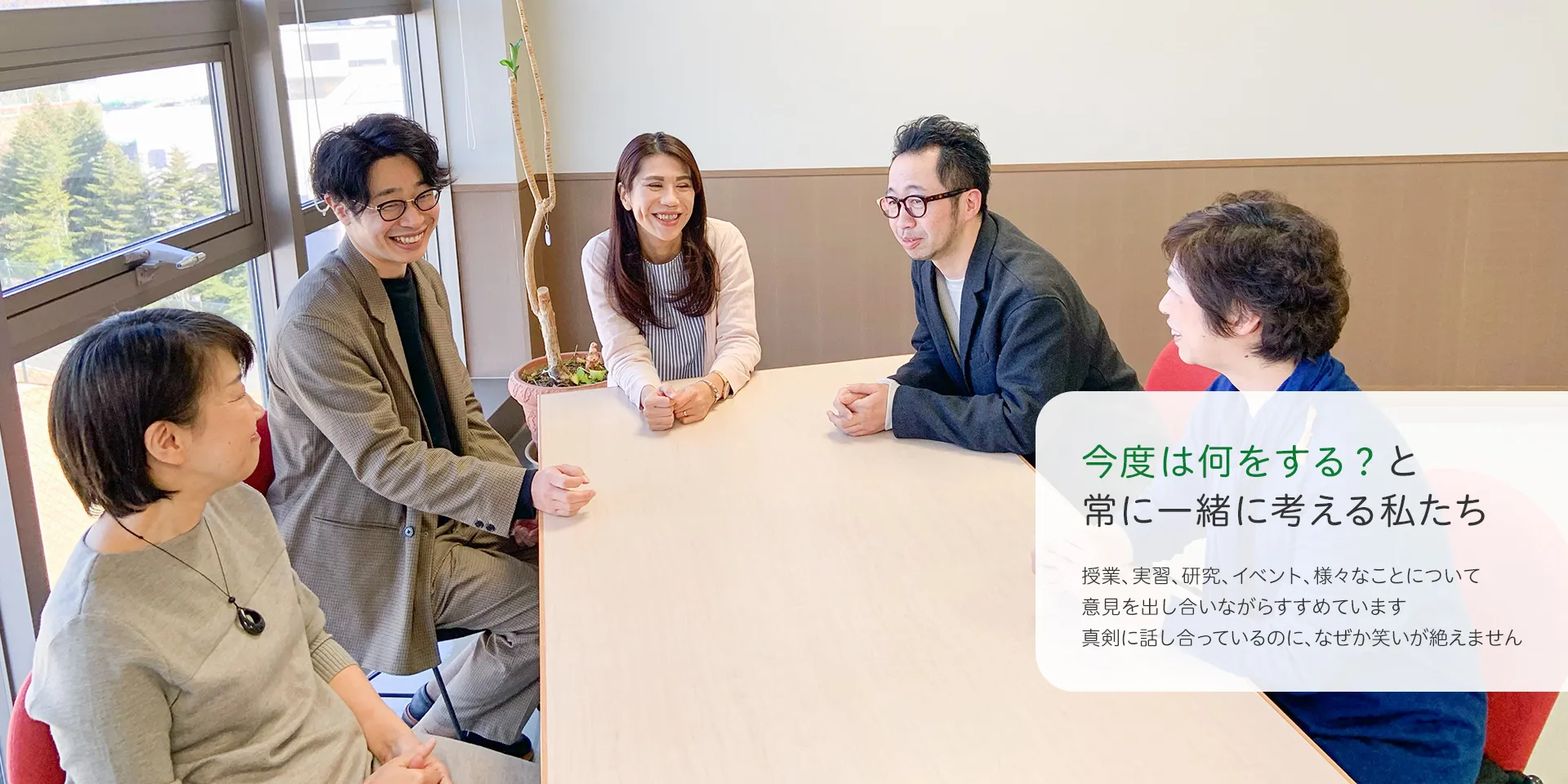 5人が明るい部屋でテーブルを囲んで談笑している様子。