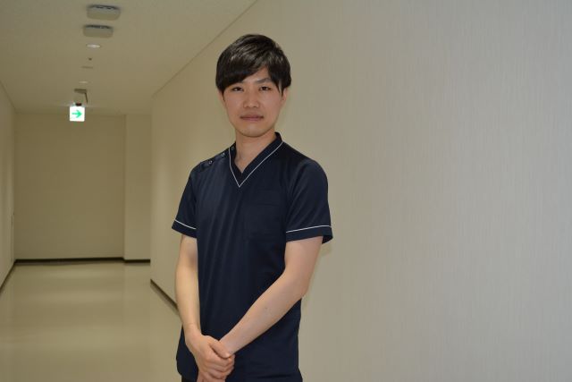 福島県立医科大学の廊下で立っている佐藤健斗さんの写真。
