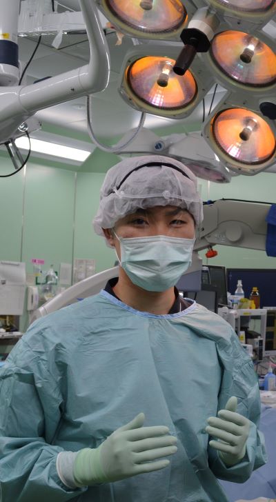 手術室で緑色の手術着を着た佐藤健斗さんが、手術の準備をしている様子。
