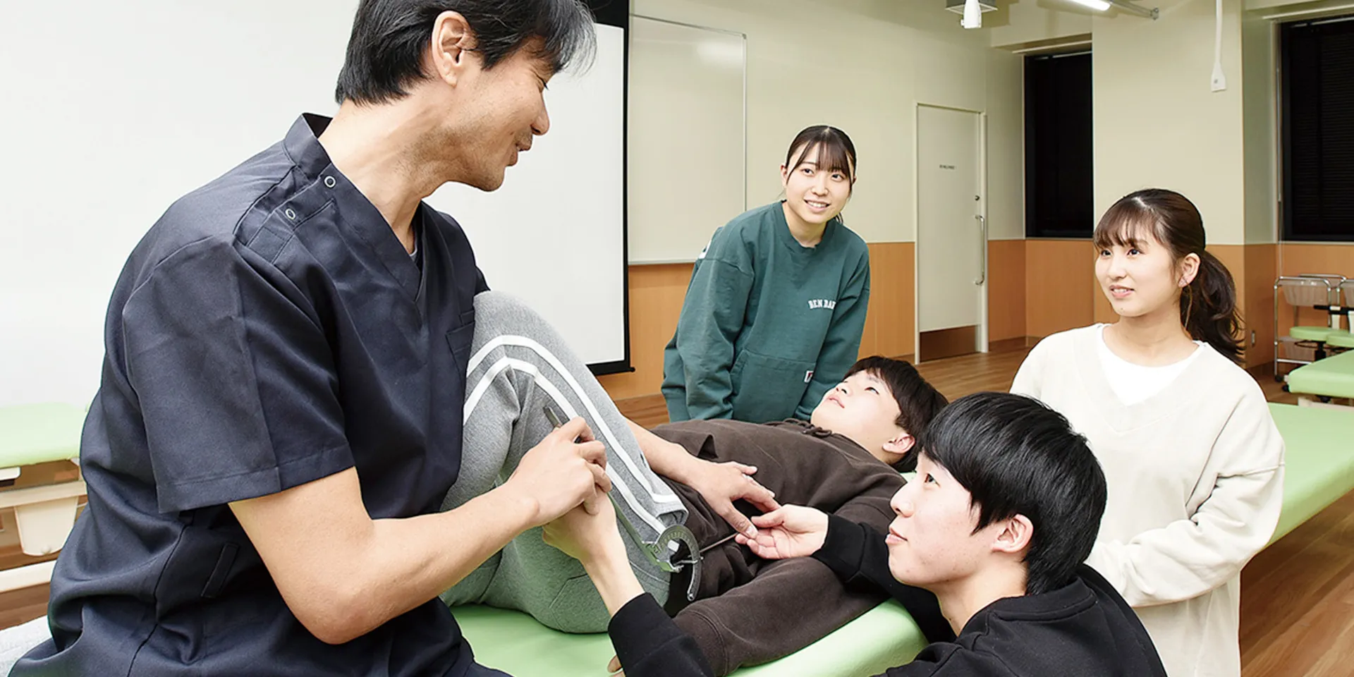 医療実習中の学生たちが、患者の身体を評価している様子。