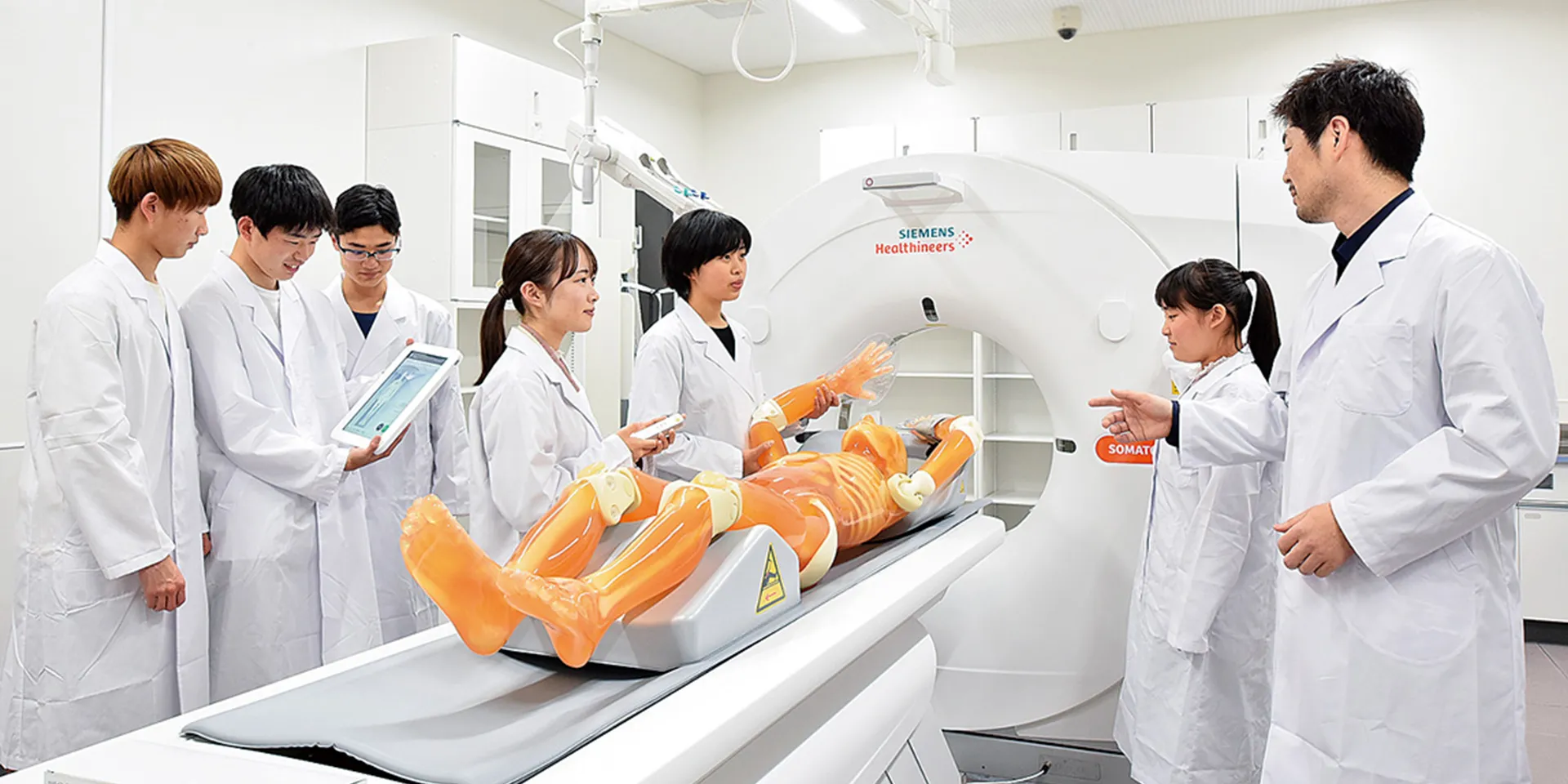 医療実習中の学生たちが、シミュレーターを使ってCTスキャンの手順を学んでいる様子。