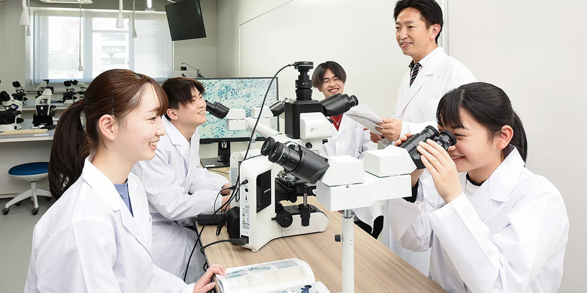 学生たちが顕微鏡を使って実習を行っている保健科学部の研究室の様子。