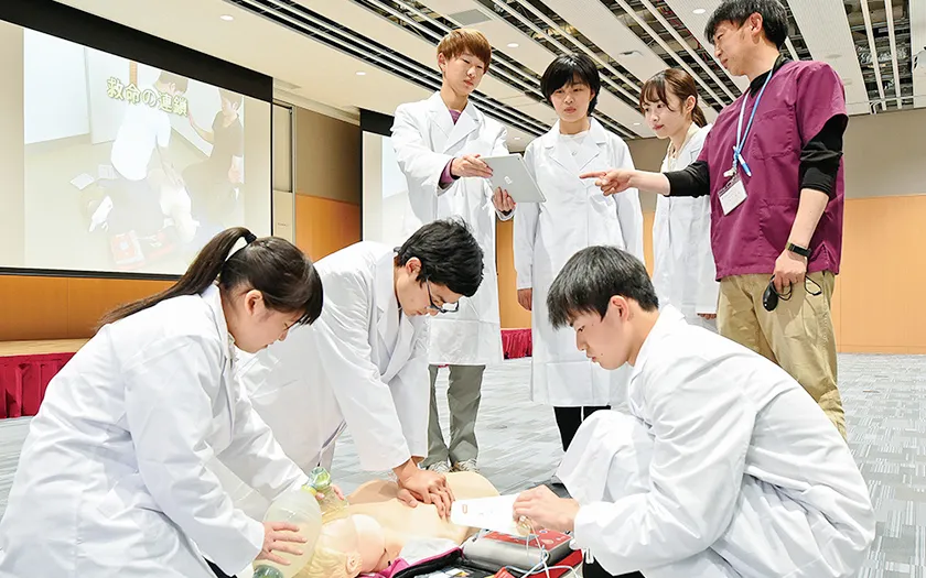 医療現場での心肺蘇生法を学ぶ学生たちが、実習用人形を使って訓練している様子。
