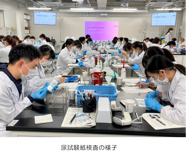 尿試験紙検査を行う学生たちが実習室で作業している様子。