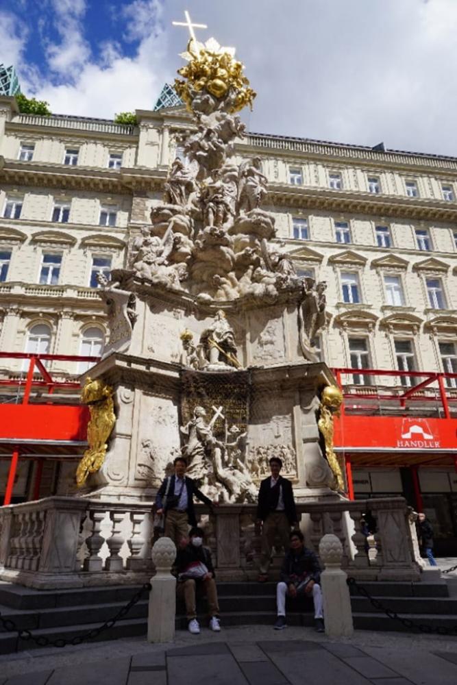 ウィーンにある17世紀のペスト終息を記念した記念柱の前でポーズをとる人々。