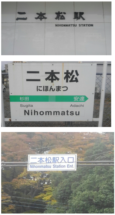 二本松駅の駅名標識と交差点の道路標識が写っており、漢字やひらがなの下にローマ字表記がある。