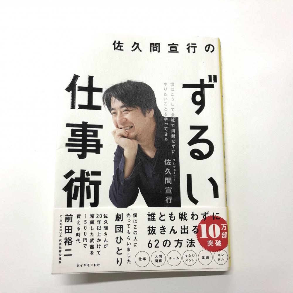 佐久間宣行さんの著書「ずるい仕事術」の表紙、笑顔でポーズをとる彼の写真が印刷されている。