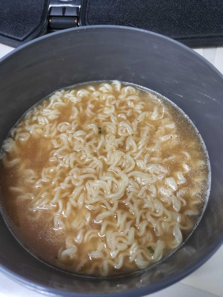 インスタントラーメンが入った鍋の中で、スープとともに湯が入った状態の写真。