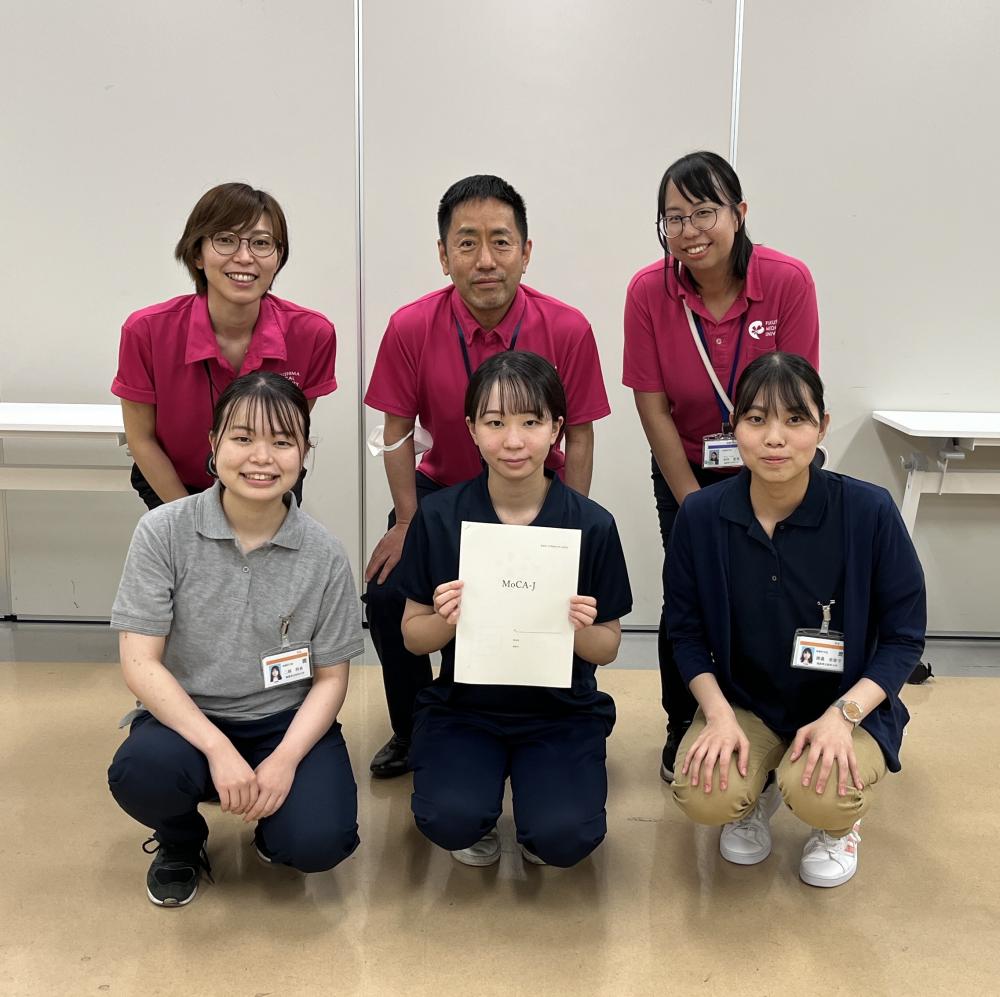 健康測定会でのスタッフと参加者の集合写真。脳の元気度を測定するための検査を行った様子。