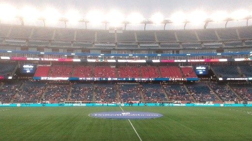サッカーの試合が行われるスタジアムの内部、観客席には多くの人々が集まっている様子。