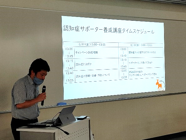 認知症サポーター養成講座で講義を行う講師と、スライドに表示されたタイムスケジュール。