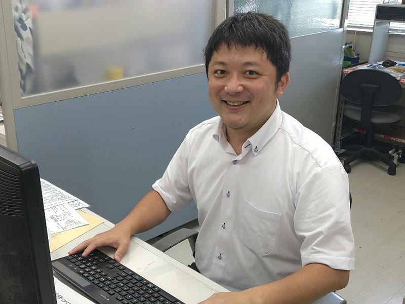 一人暮らしを始めた作業療法学科の教員が、デスクで笑顔でパソコンに向かっている様子。