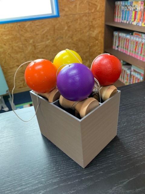 3Dプリンターで作られたカラフルなけん玉ボックスが、机の上に置かれている様子。