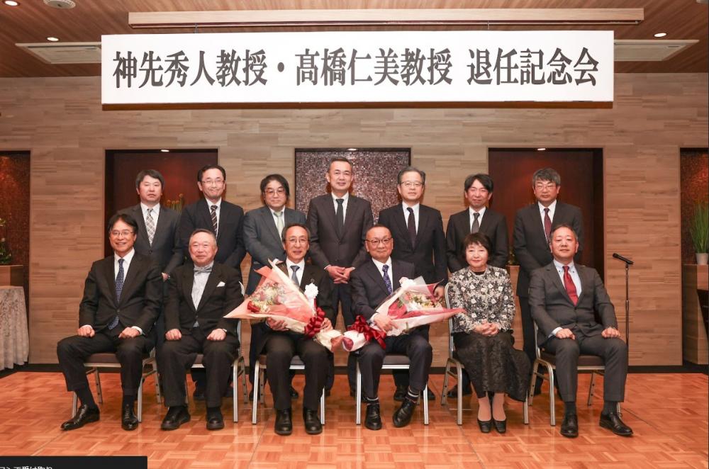 神先秀人教授と高橋仁美教授の退官記念会での集合写真。教授たちが花束を持ち、感謝の意を表しています。