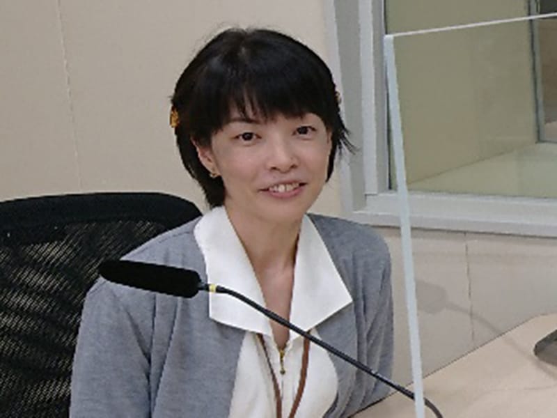 理学療法士としての活動について話す女性が、マイクの前で座っている様子。