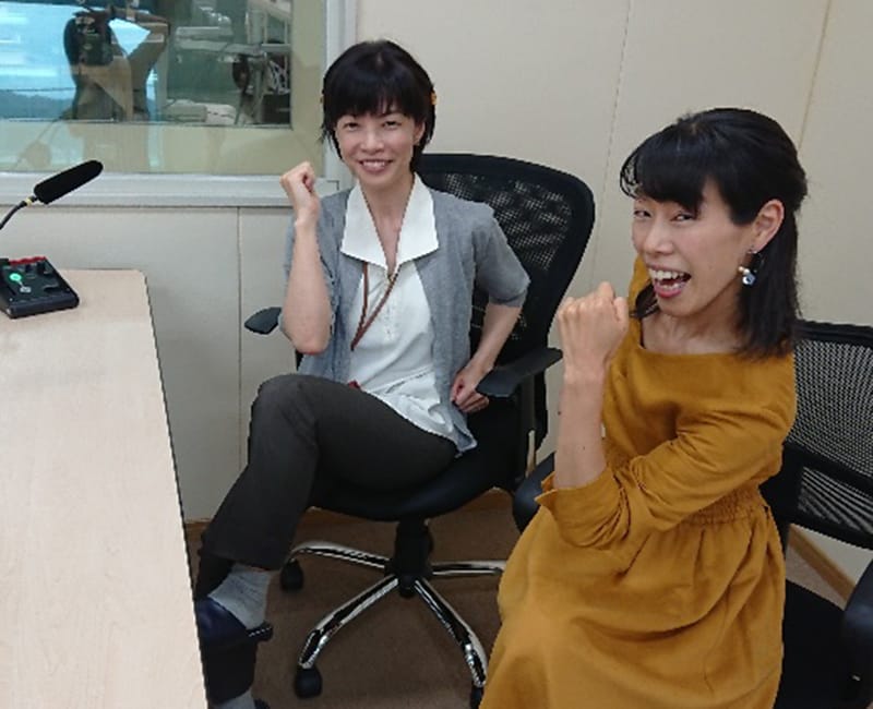 ラジオ番組収録中に運動を勧める二人の女性が笑顔でポーズをとっている様子。