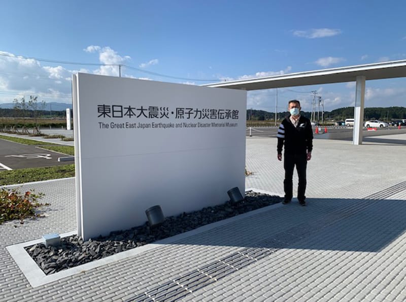 東日本大震災・原子力災害伝承館の前でマスクを着用した男性が立っている写真。