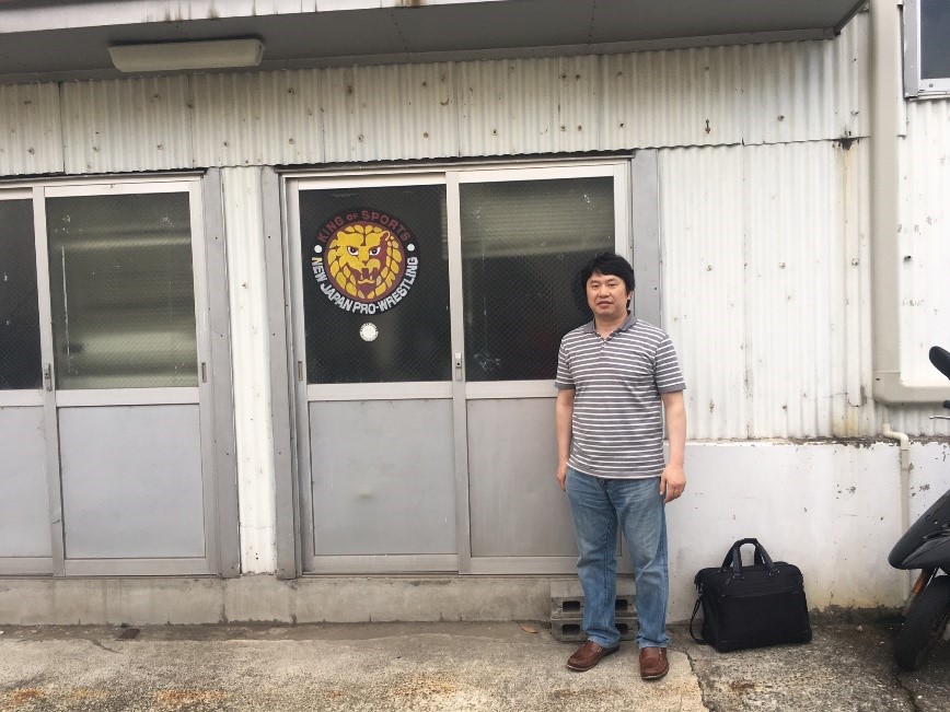 新日本プロレス道場の前に立つ男性が写っている写真。