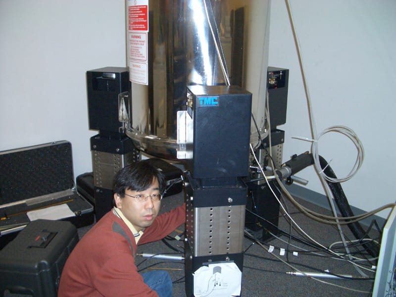 実験機器の前で作業する研究者の姿。放射線技術の研究に取り組む様子が伺える。