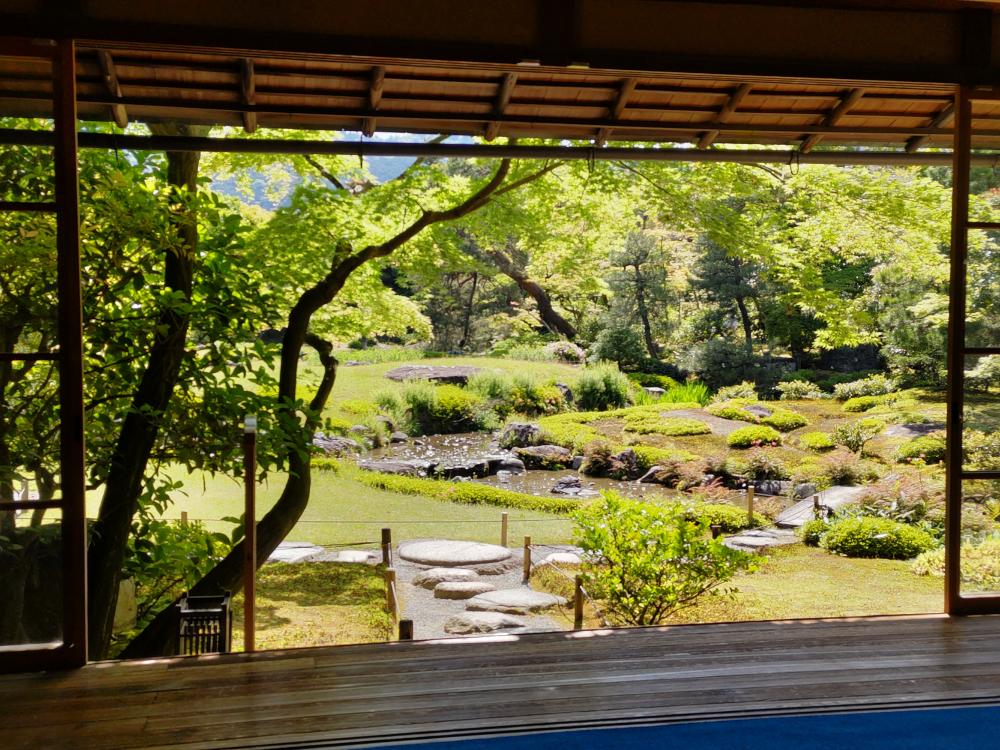 無鄰菴の庭園風景、青もみじが映える里山の景色と小川が見える。