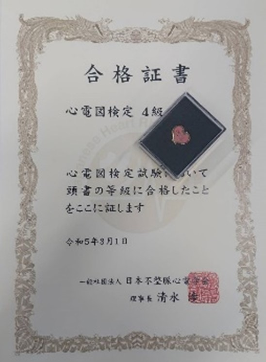 心電図検定4級合格証書と認定バッジが写った画像。