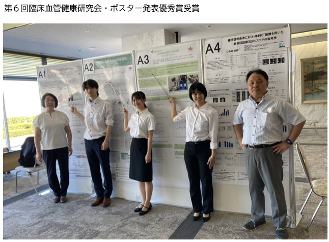 臨床検査学科の4年生が研究成果を発表するポスターの前で立っている様子。