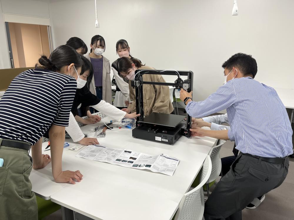 3Dプリンターの組み立て作業を行う学生たちが集まっている様子。