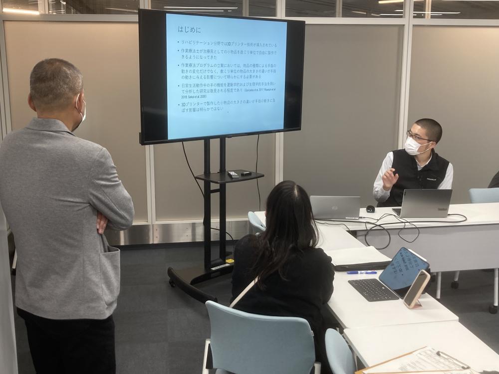 作業療法学科の定期教員勉強会で、講師がプレゼンテーションを行っている様子。参加者は真剣に聞き入っている。