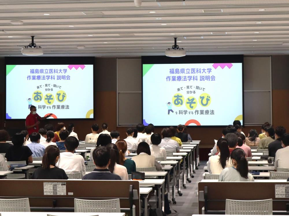 作業療法学科説明会での講義風景、参加者がスクリーンを見つめている様子。