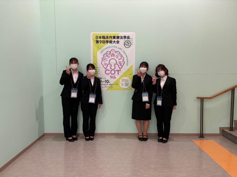 作業療法学科の学生たちが学会でポスター発表を行うために集合し、笑顔でポーズをとっている様子。