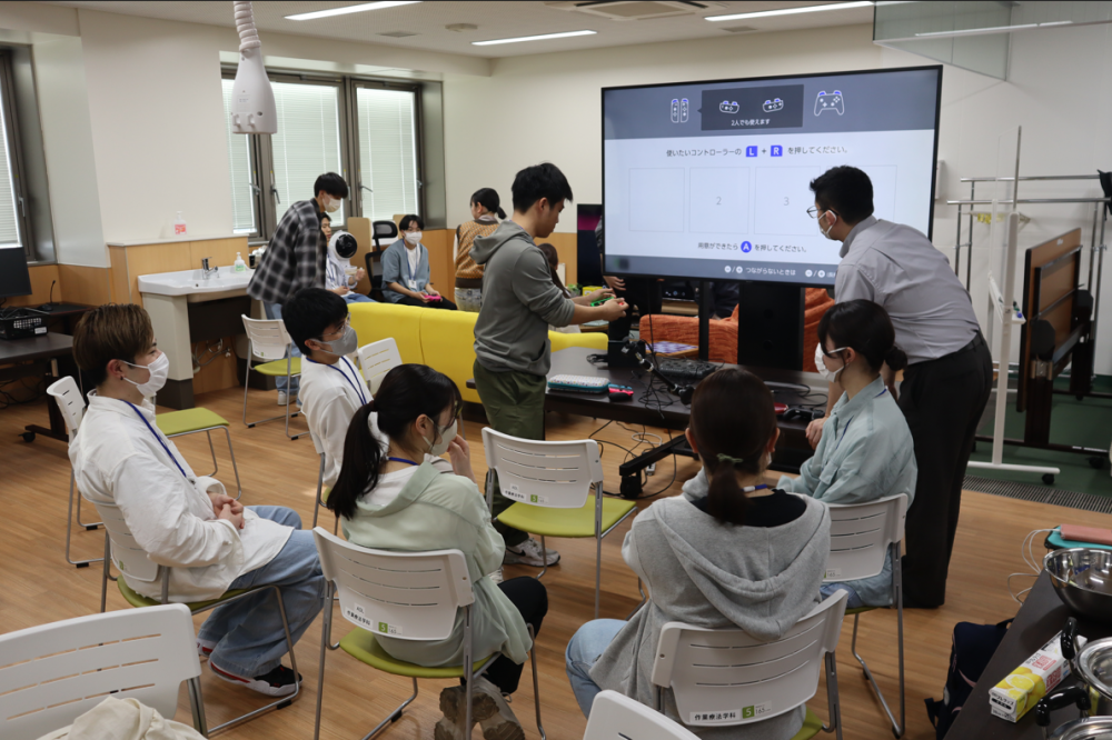 作業療法学科の学生たちがゲームコースの講義を受け、PS5やNintendo Switchを体験している様子。