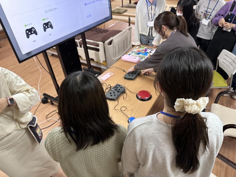 ゲームコース第2回開催の様子。参加者がテレビ画面を見ながらゲームコントローラーを操作している。