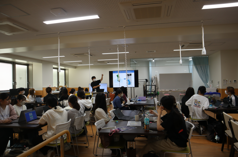 3Dプリンターコースの授業風景。講師が画面を指し示し、学生たちがパソコンを使って学んでいる様子。