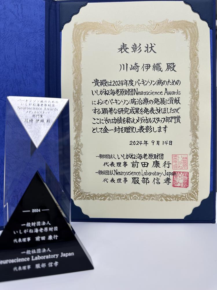 川﨑伊織講師が「パーキンソン病のためのいしがね海老原財団 Neuroscience Awards」を受賞した表彰状と記念品の画像。