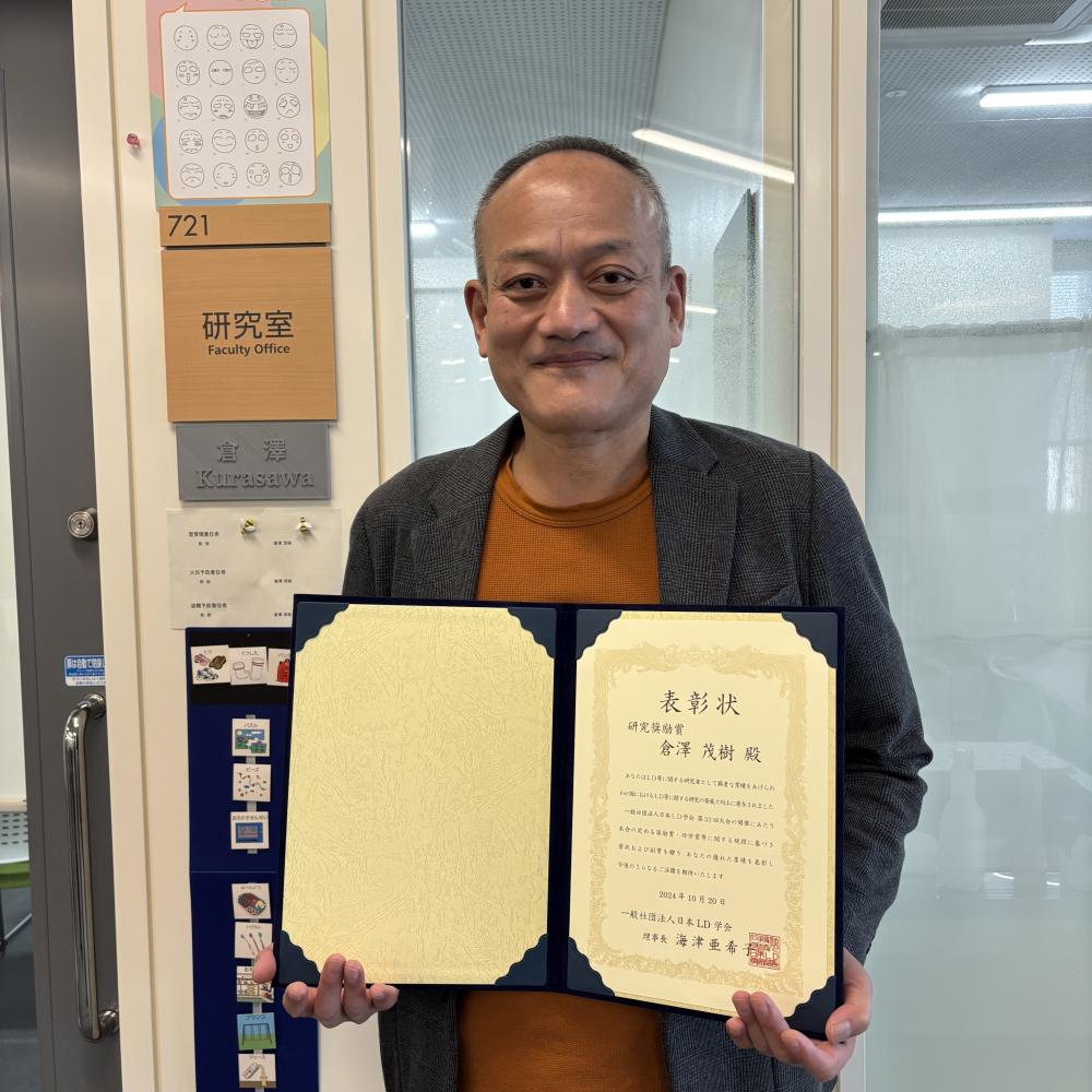 作業療法学科の倉澤教授が研究奨励賞を受賞し、賞状を持って微笑んでいる様子。