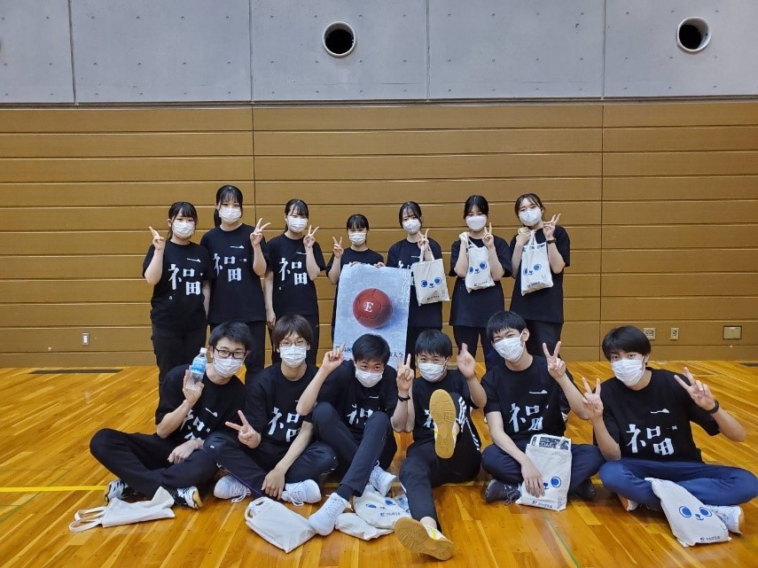 障がい者スポーツ大会に参加したボランティア学生たちが、笑顔でポーズをとっている様子。