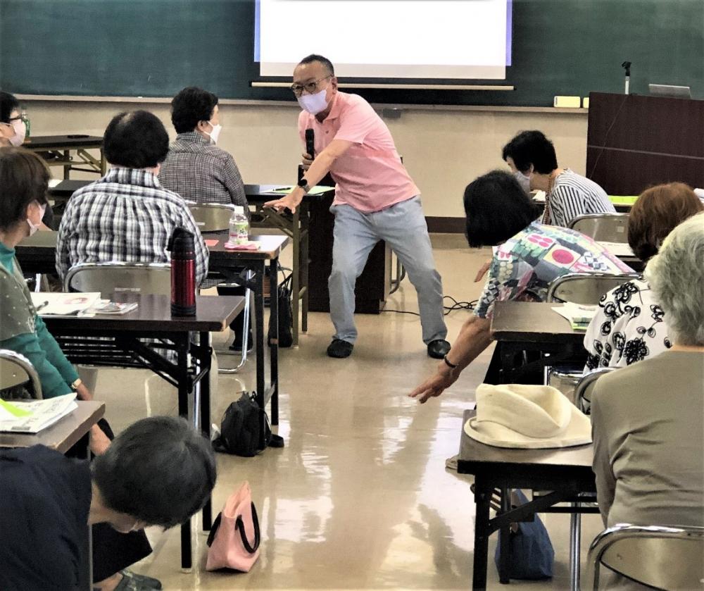 「1日1動！リアル体験教室」で講師が参加者に指導している様子。参加者は座って聴講中。