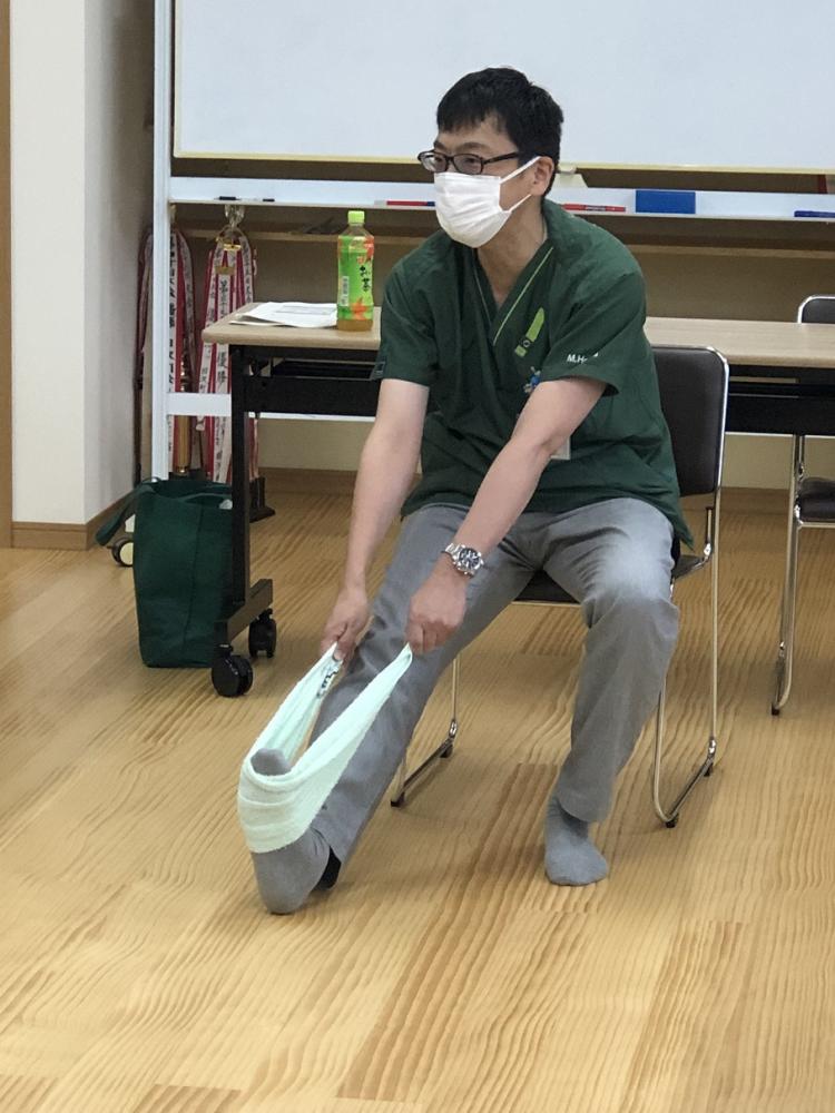 理学療法学科の教員が、座った状態でストレッチを行っている様子。