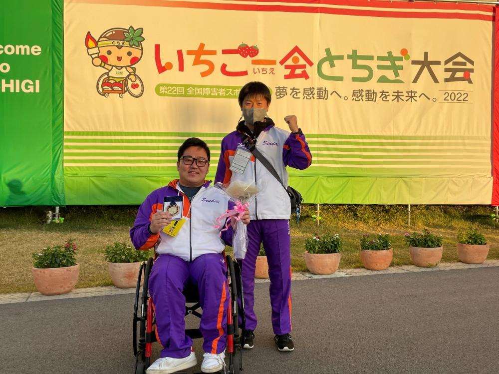 障がい者スポーツ大会で笑顔の選手とサポーターが記念撮影している様子。