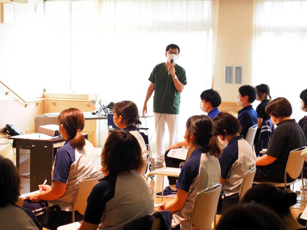 理学療法学科の星真行助教が褥瘡予防研修会で講演を行っている様子。参加者は座って聴講中。
