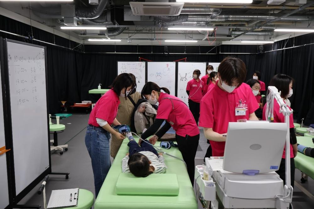 子どもコホート調査を実施する福島県立医科大学の教員と学生たちが、ピンクのTシャツを着て活動している様子。