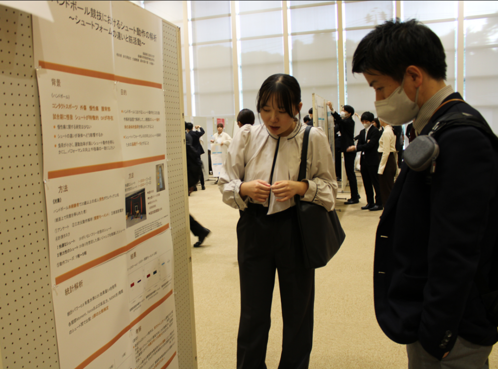理学療法学科の学生がポスター発表を行い、他の学生と情報を共有している様子。