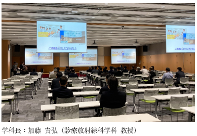 福島駅前キャンパスの多目的ホールで、加藤貴弘学科長が施設紹介を行っている様子。参加者が座っている。