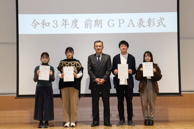 令和3年度前期GPA表彰式で表彰状を持つ学生たちと矢吹学部長の集合写真。