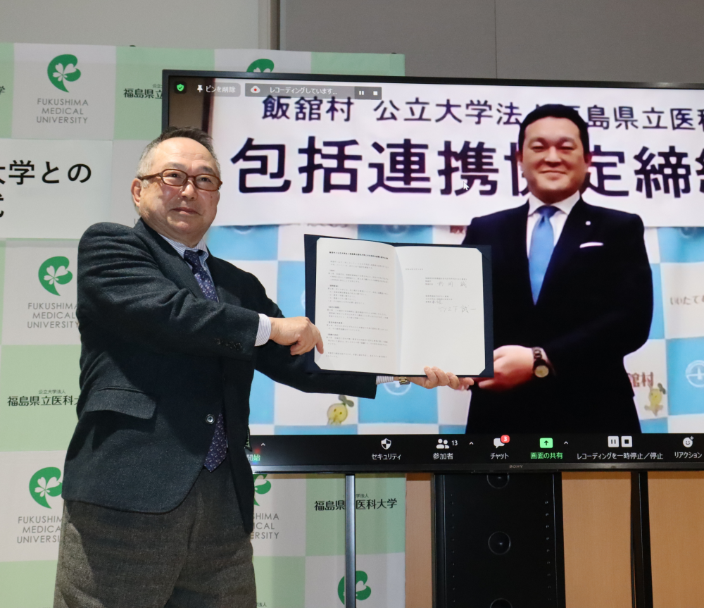 飯舘村との包括連携協定を締結した福島県立医科大学の関係者が、書類を持って記念撮影している様子。